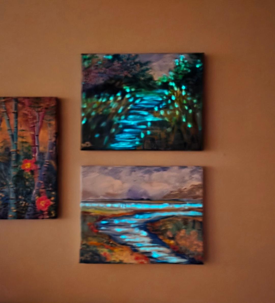 Two canvases in a darkened room, water and light paths glowing aqua from phosphorescent accents